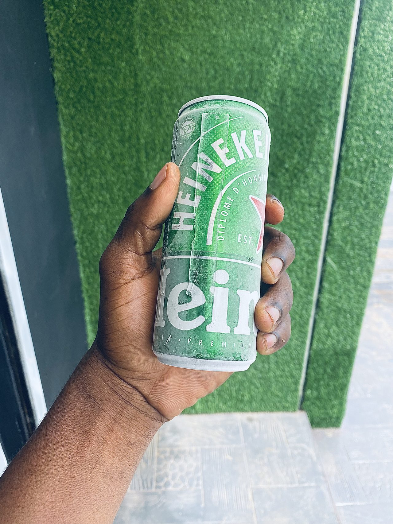 Chilled can of beer held in hand outside the bar